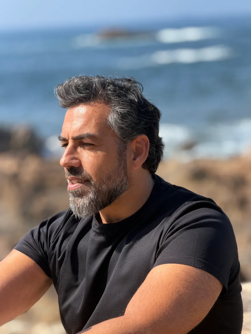 Mário Ribeiro, de perfil, junto ao mar
